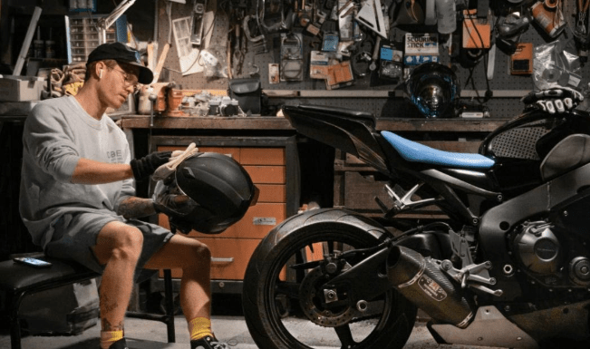 Motorcycle rider cleaning helmet visor